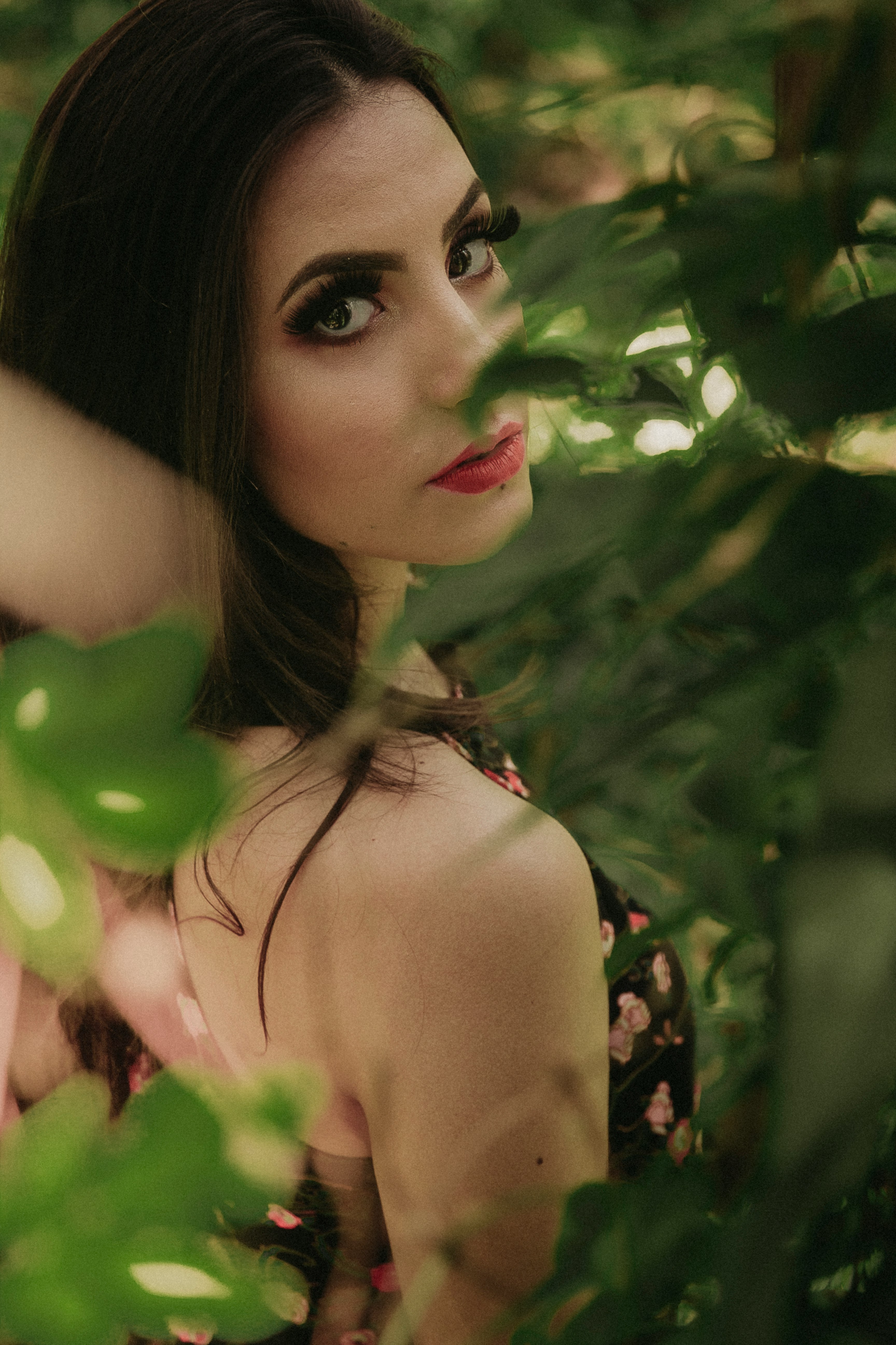 selective focus of woman surrounded by green leafy plants at daytime